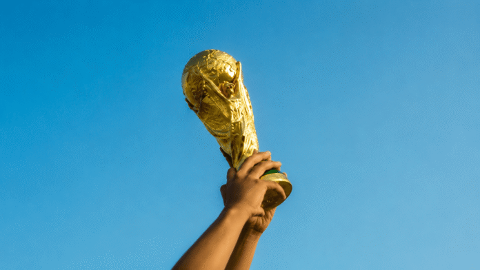 Hands raising a championship trophy against a clear blue sky